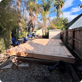 Wooden diy deck kit under construction in a backyard with tools and materials scattered around.